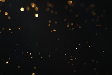 Photo of Beautiful shiny golden glitter on black background, closeup