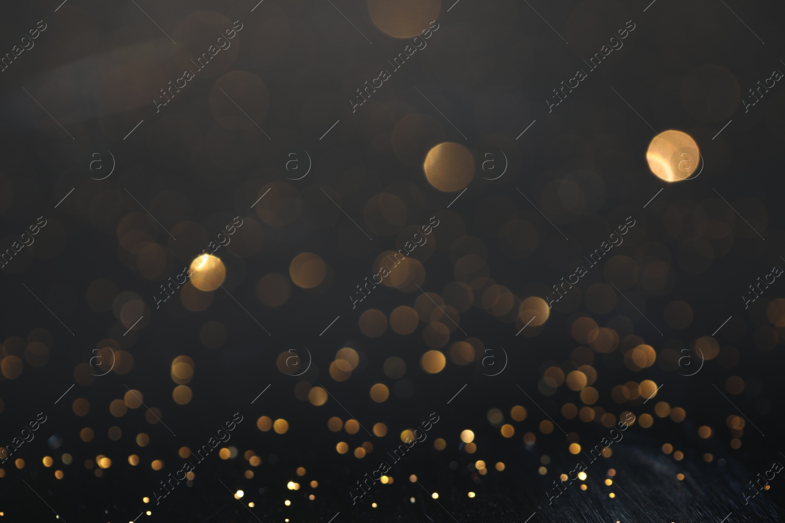 Photo of Beautiful shiny golden glitter on black background, closeup