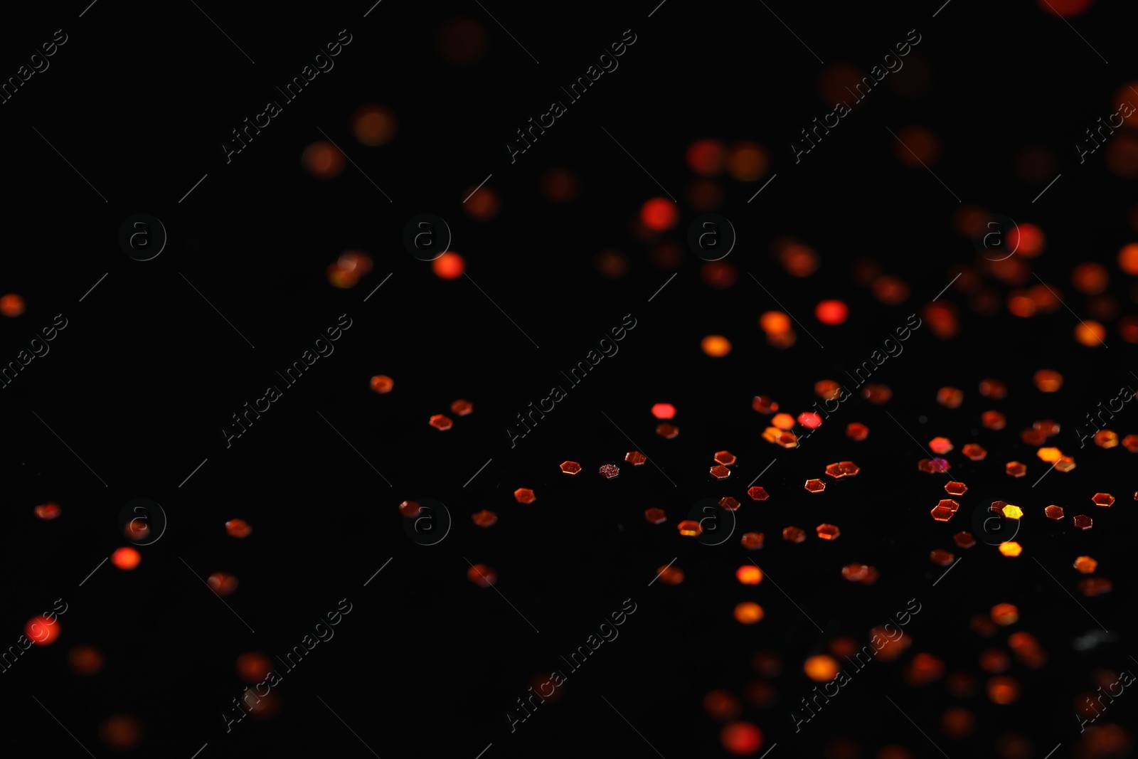 Photo of Beautiful shiny golden glitter on black background, closeup