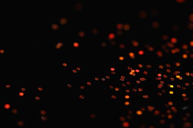 Photo of Beautiful shiny golden glitter on black background, closeup