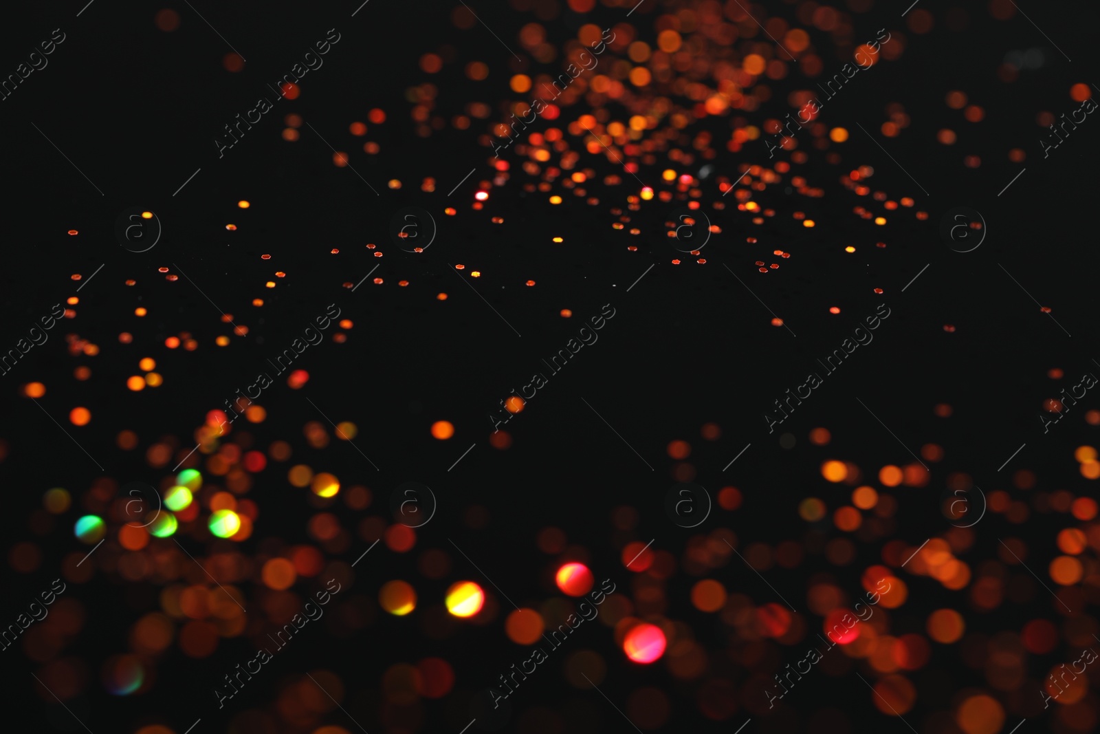 Photo of Beautiful shiny golden glitter on black background, closeup