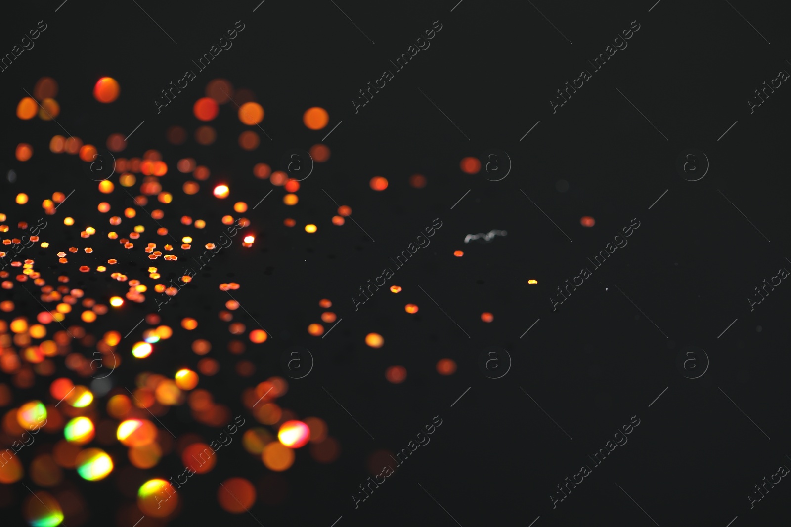 Photo of Beautiful shiny golden glitter on black background, closeup