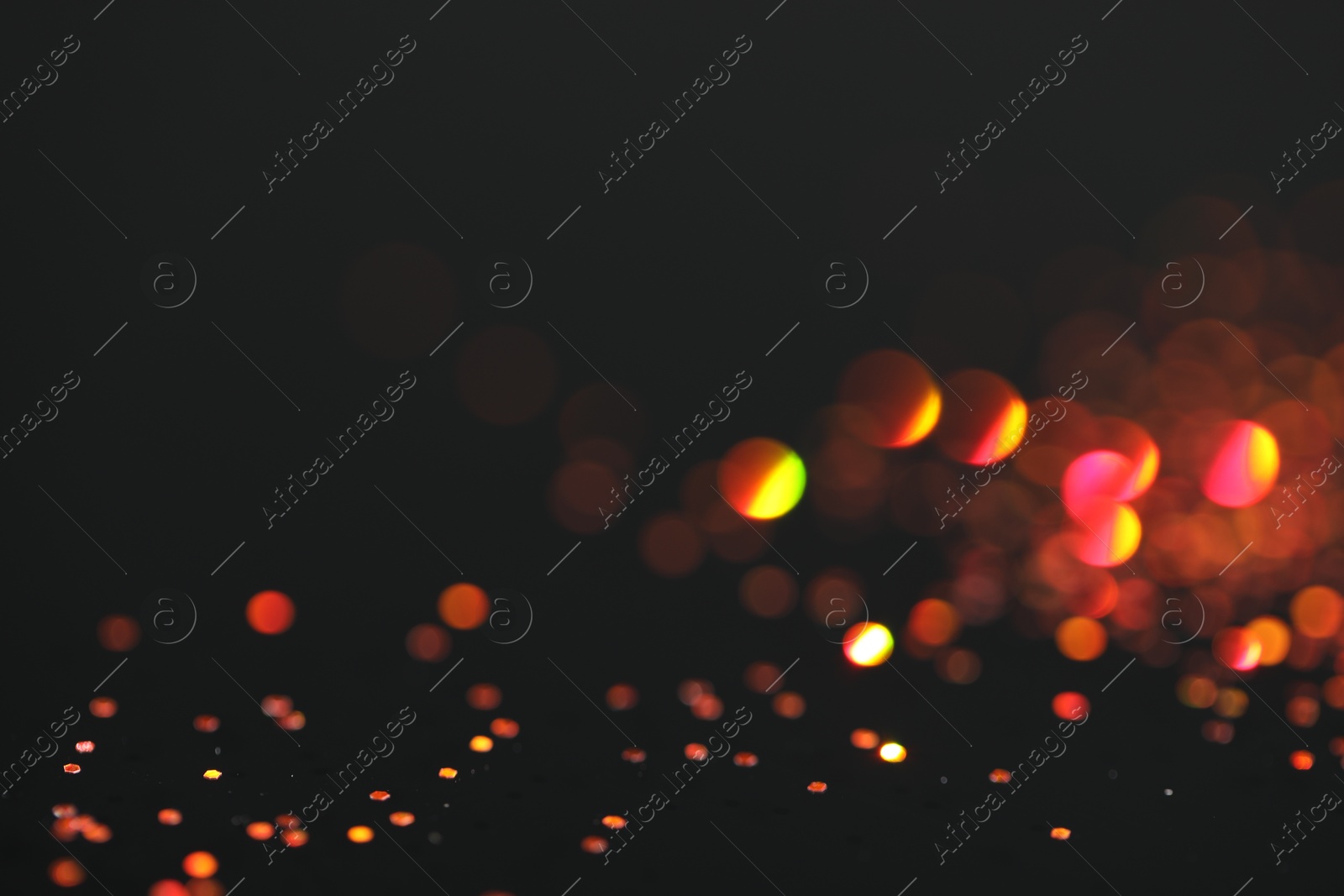 Photo of Beautiful shiny golden glitter on black background, closeup