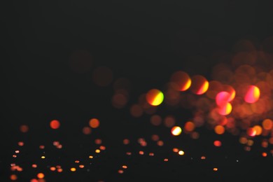 Photo of Beautiful shiny golden glitter on black background, closeup