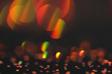 Photo of Beautiful shiny golden glitter on black background, closeup