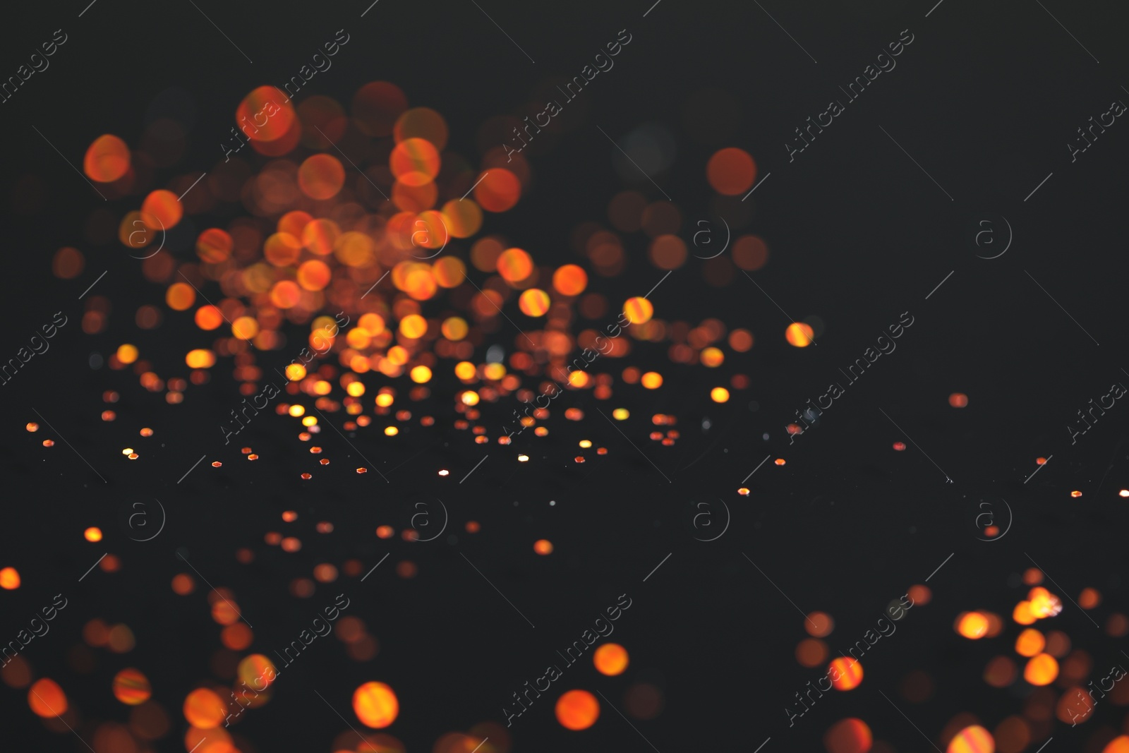 Photo of Beautiful shiny golden glitter on black background, closeup