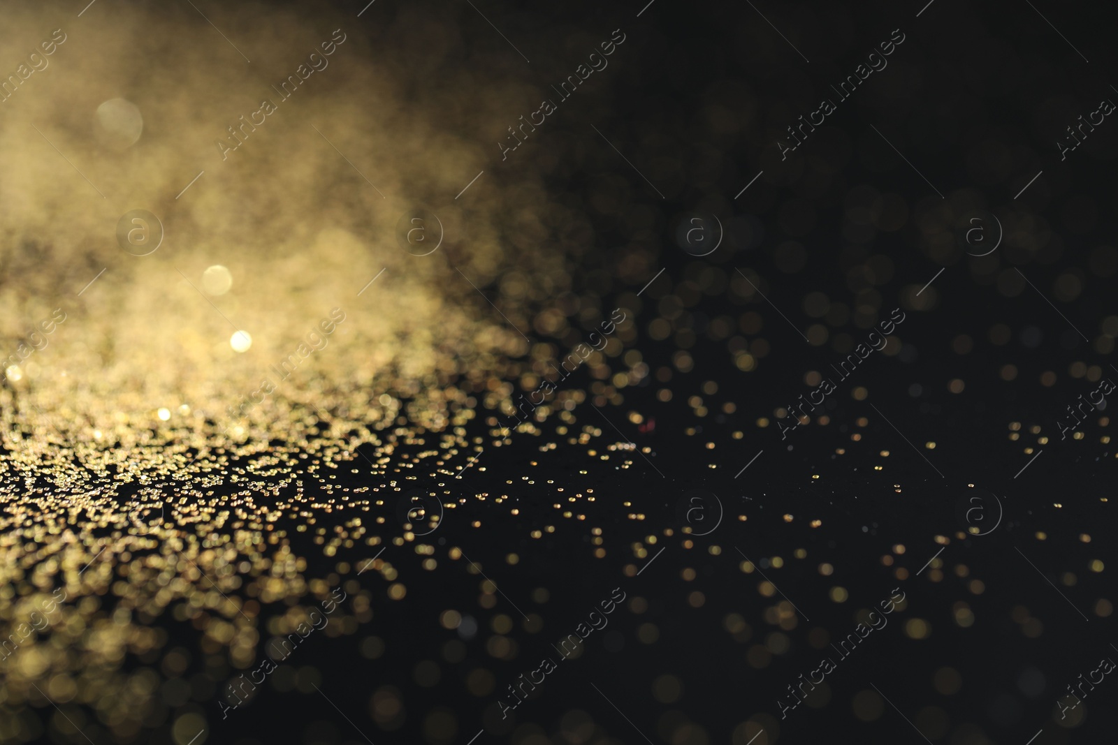 Photo of Beautiful shiny golden glitter on black background, closeup