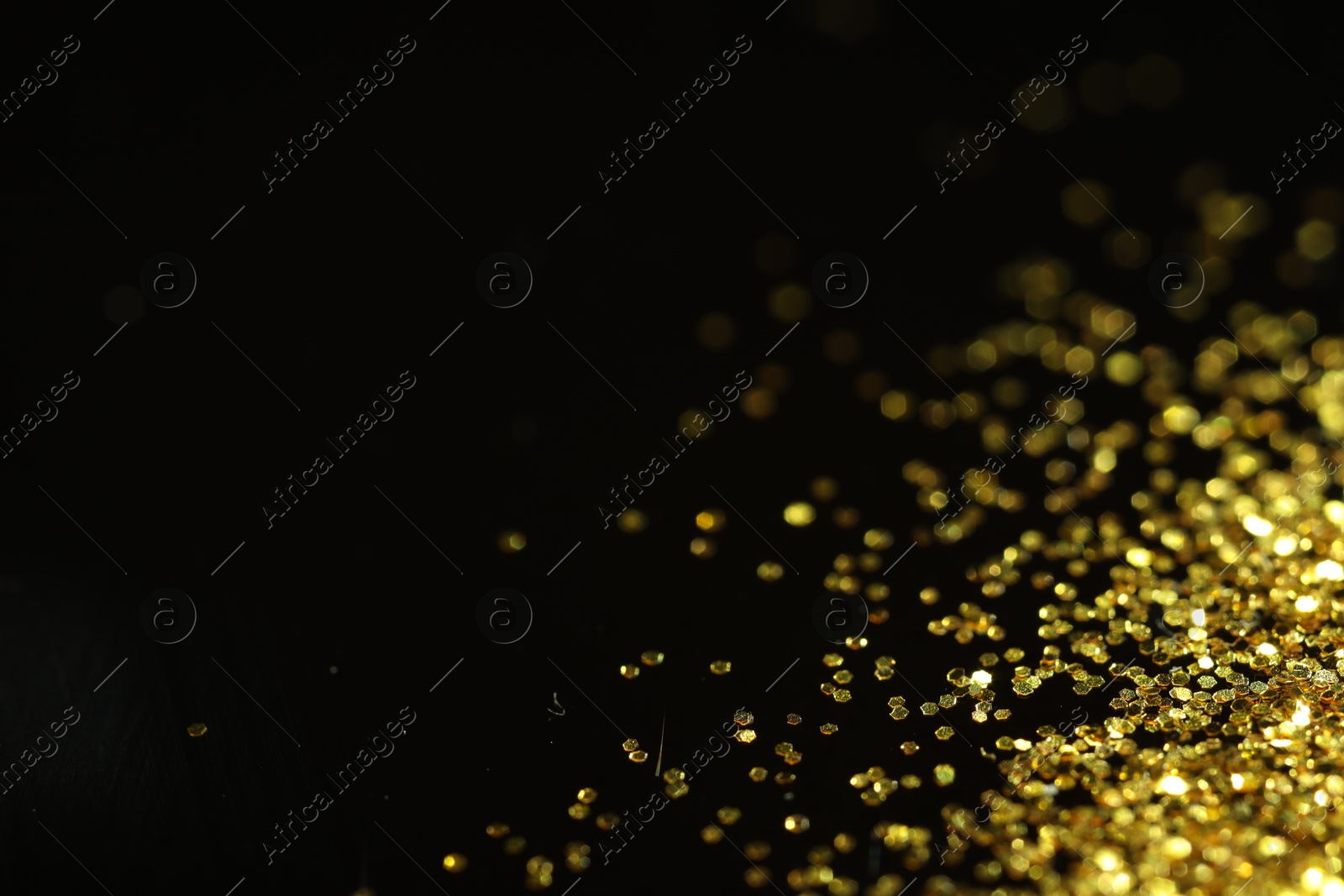 Photo of Beautiful shiny golden glitter on black background, closeup