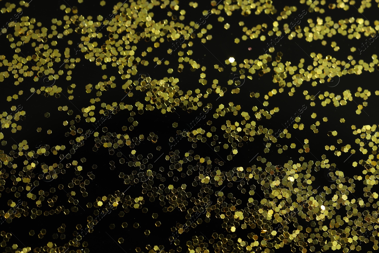 Photo of Beautiful shiny golden glitter on black background, top view