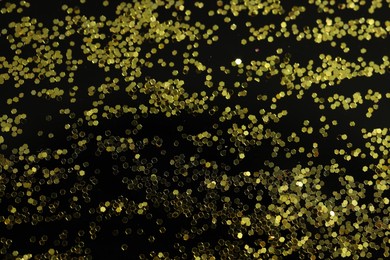 Photo of Beautiful shiny golden glitter on black background, top view