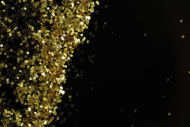 Photo of Beautiful shiny golden glitter on black background, top view