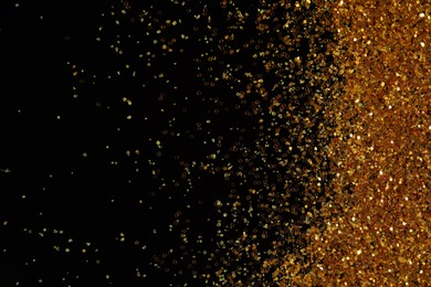 Photo of Beautiful shiny golden glitter on black background, top view