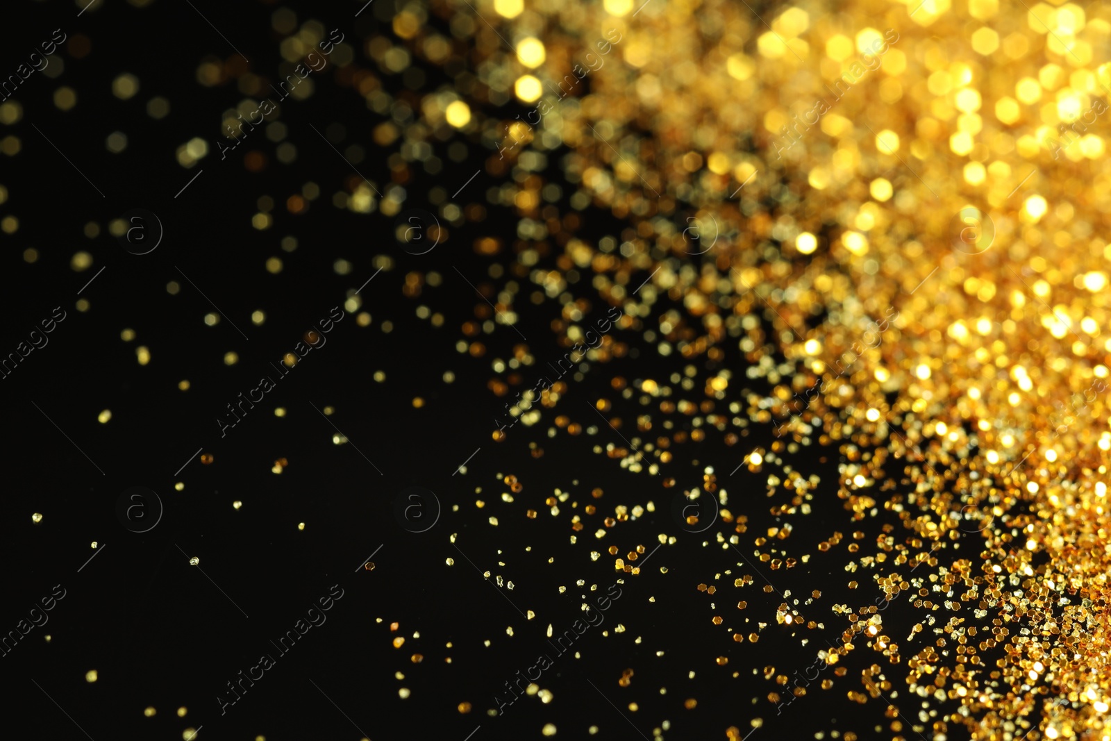 Photo of Beautiful shiny golden glitter on black background, closeup