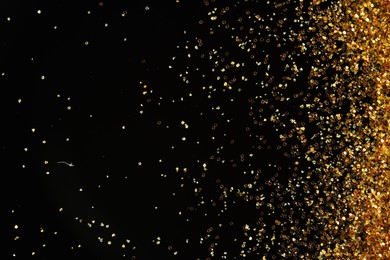 Photo of Beautiful shiny golden glitter on black background, top view