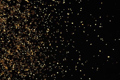 Photo of Beautiful shiny golden glitter on black background, top view