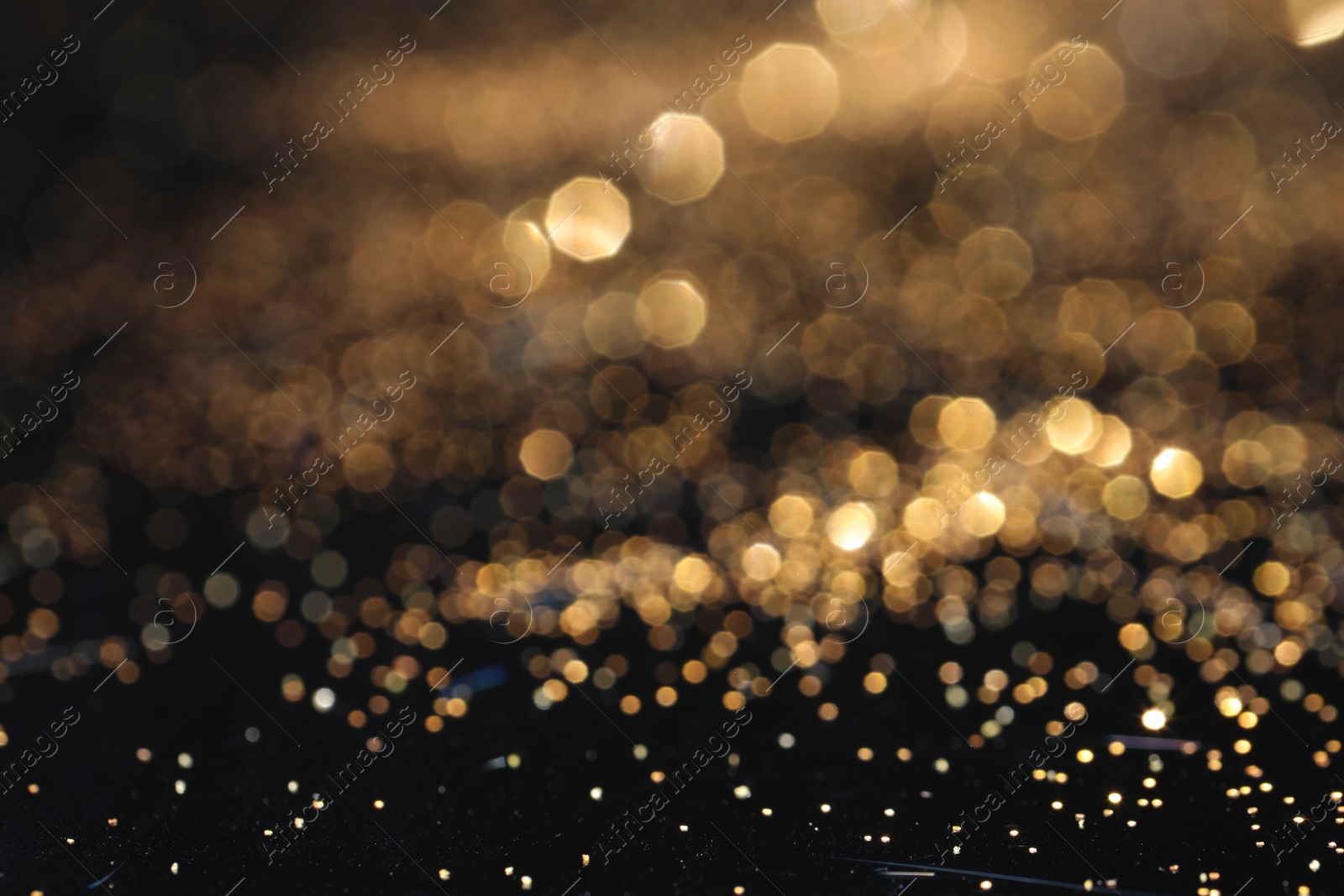 Photo of Beautiful shiny golden glitter on black background, closeup