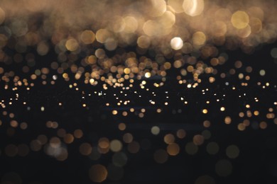 Photo of Beautiful shiny golden glitter on black background, closeup