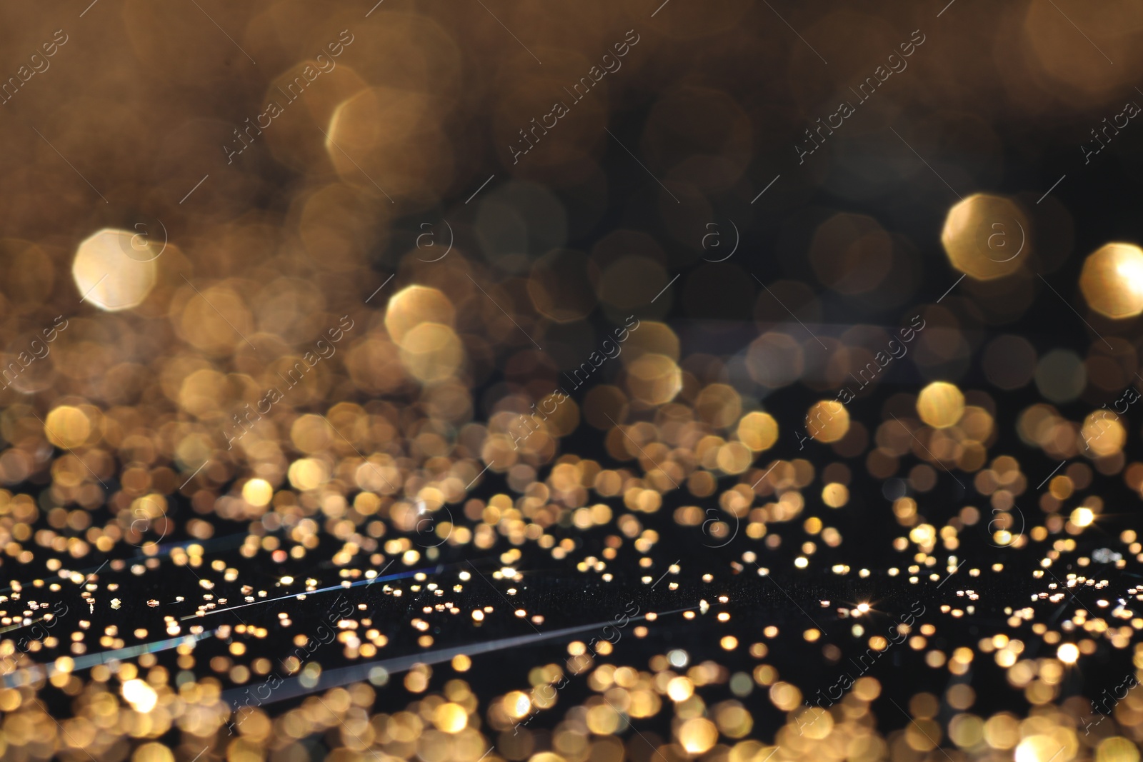 Photo of Beautiful shiny golden glitter on black background, closeup