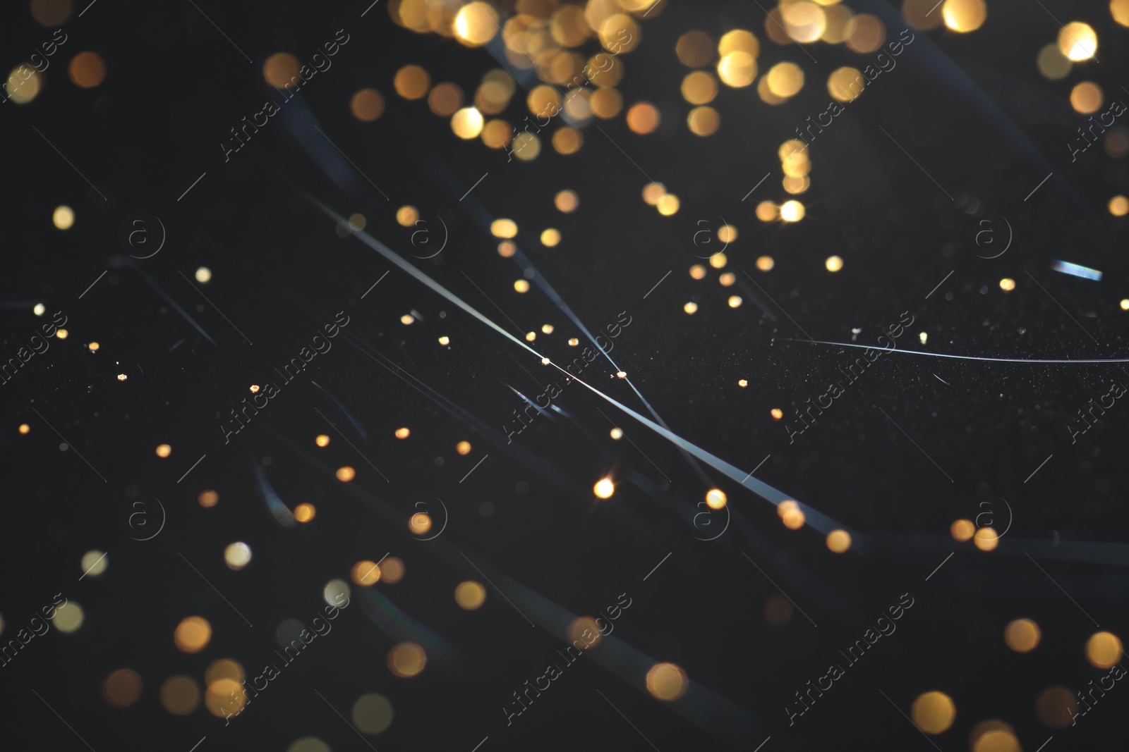 Photo of Beautiful shiny golden glitter on black background, closeup