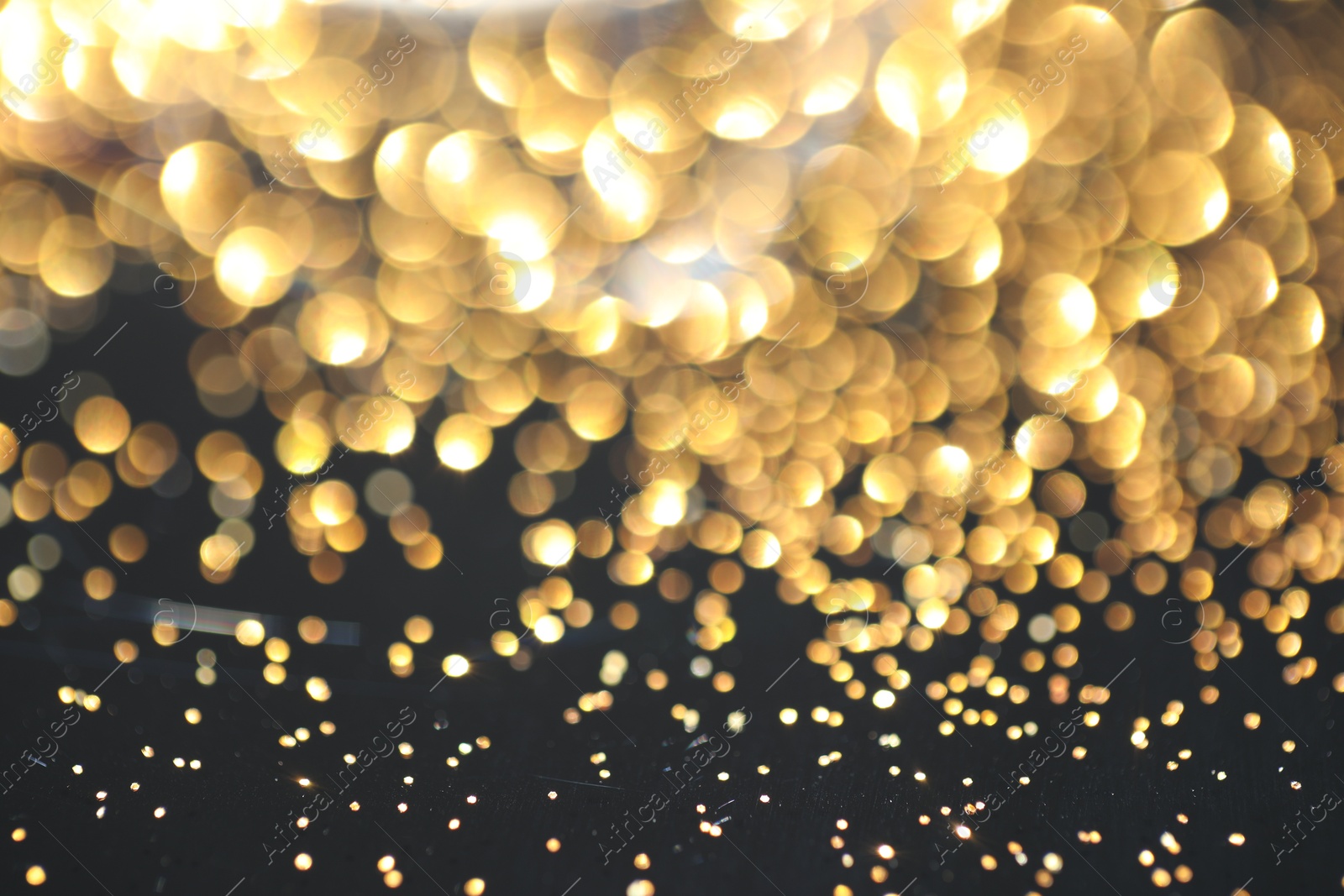 Photo of Beautiful shiny golden glitter on black background, closeup