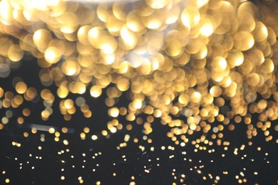 Photo of Beautiful shiny golden glitter on black background, closeup