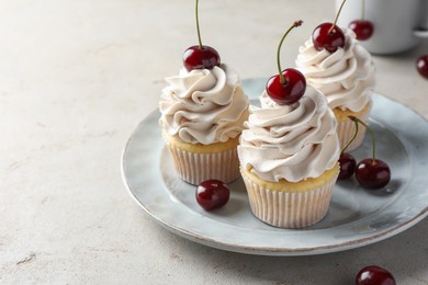 Photo of Delicious cupcakes with cream and cherries on light textured table, closeup. Space for text