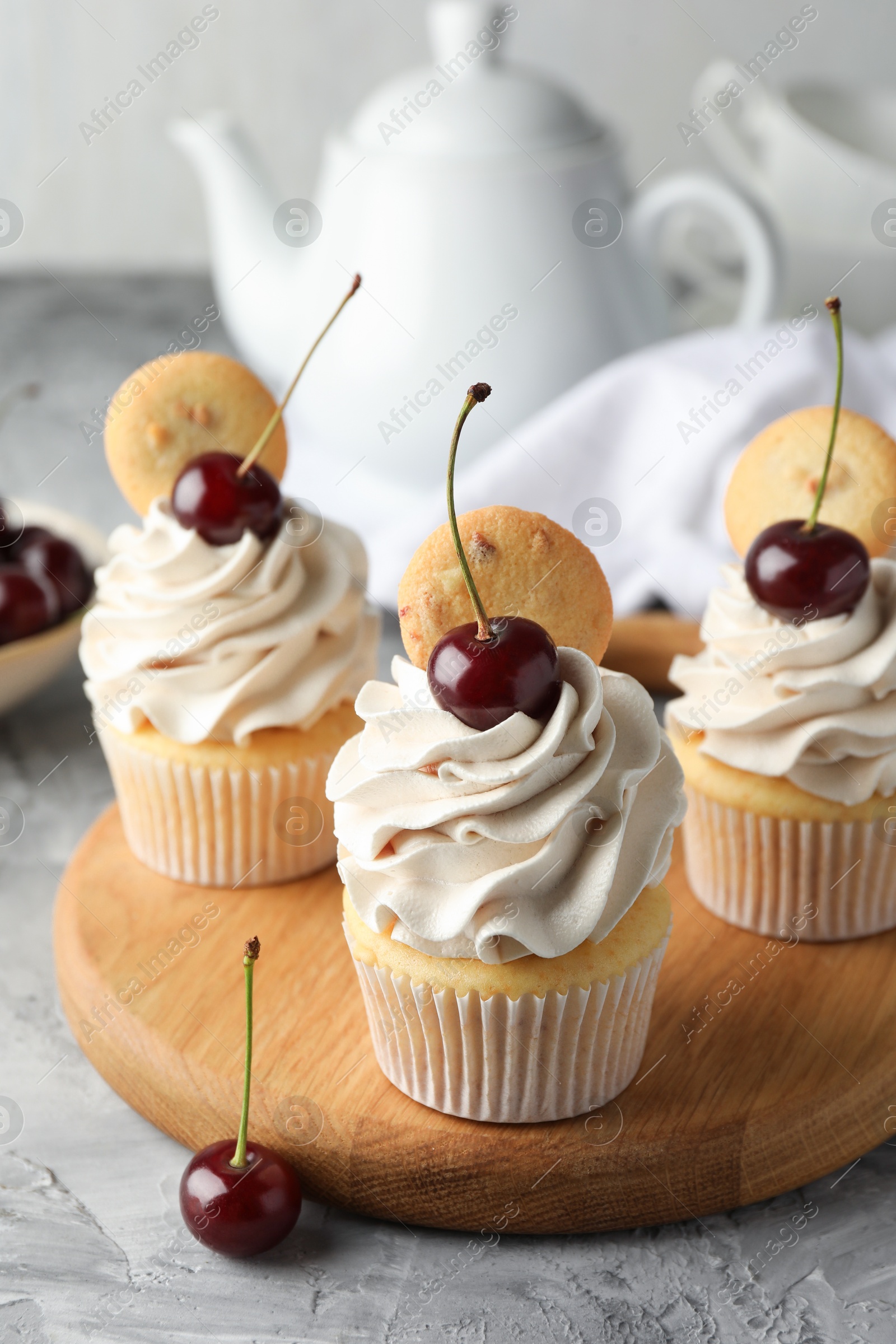 Photo of Delicious cupcakes with cherries and cookies on grey textured table