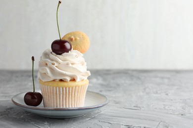 Photo of Delicious cupcake with cherries and cookie on grey textured table, closeup. Space for text