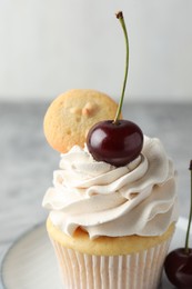 Photo of Delicious cupcake with cherries and cookie on grey table, closeup