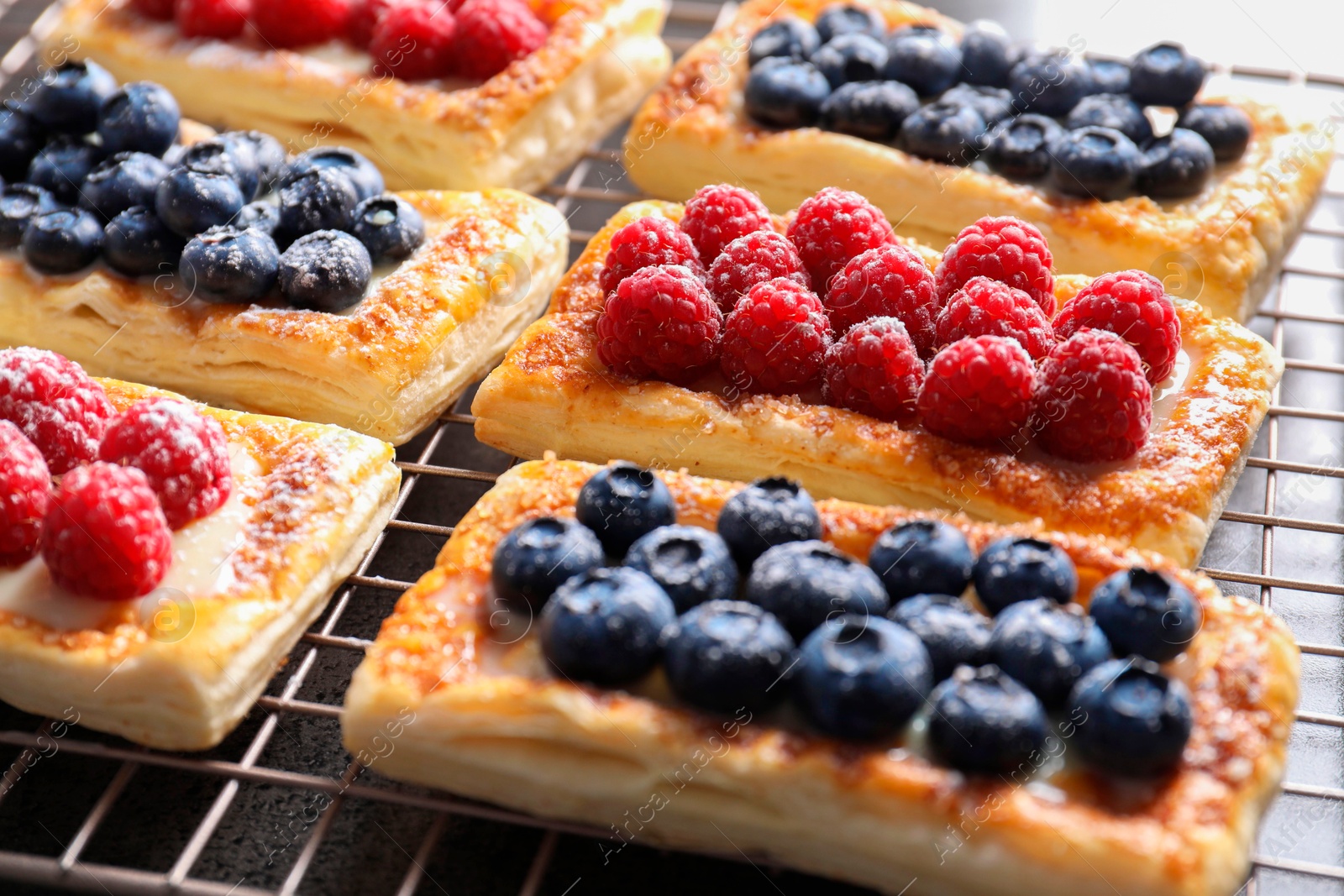 Photo of Tasty puff pastries with berries on grey table, closeup