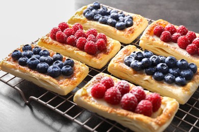 Photo of Tasty puff pastries with berries on grey table, closeup