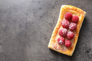 Photo of Tasty puff pastry with raspberries on grey table, top view. Space for text