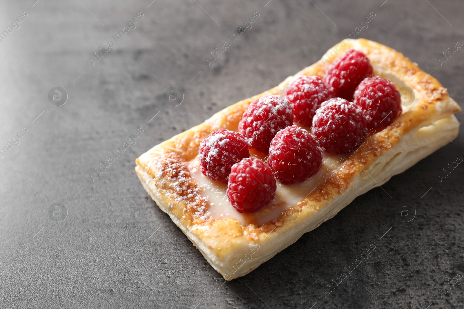 Photo of Tasty puff pastry with raspberries on grey table, closeup