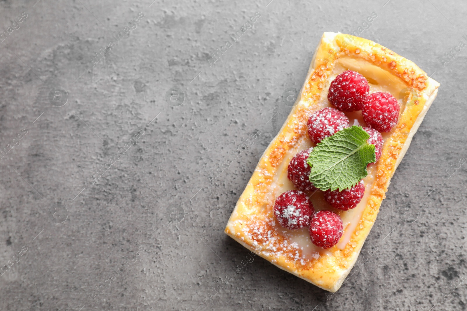 Photo of Tasty puff pastry with raspberries and mint on grey table, top view. Space for text