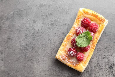 Tasty puff pastry with raspberries and mint on grey table, top view. Space for text