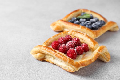 Photo of Tasty puff pastries with berries on white table, closeup. Space for text