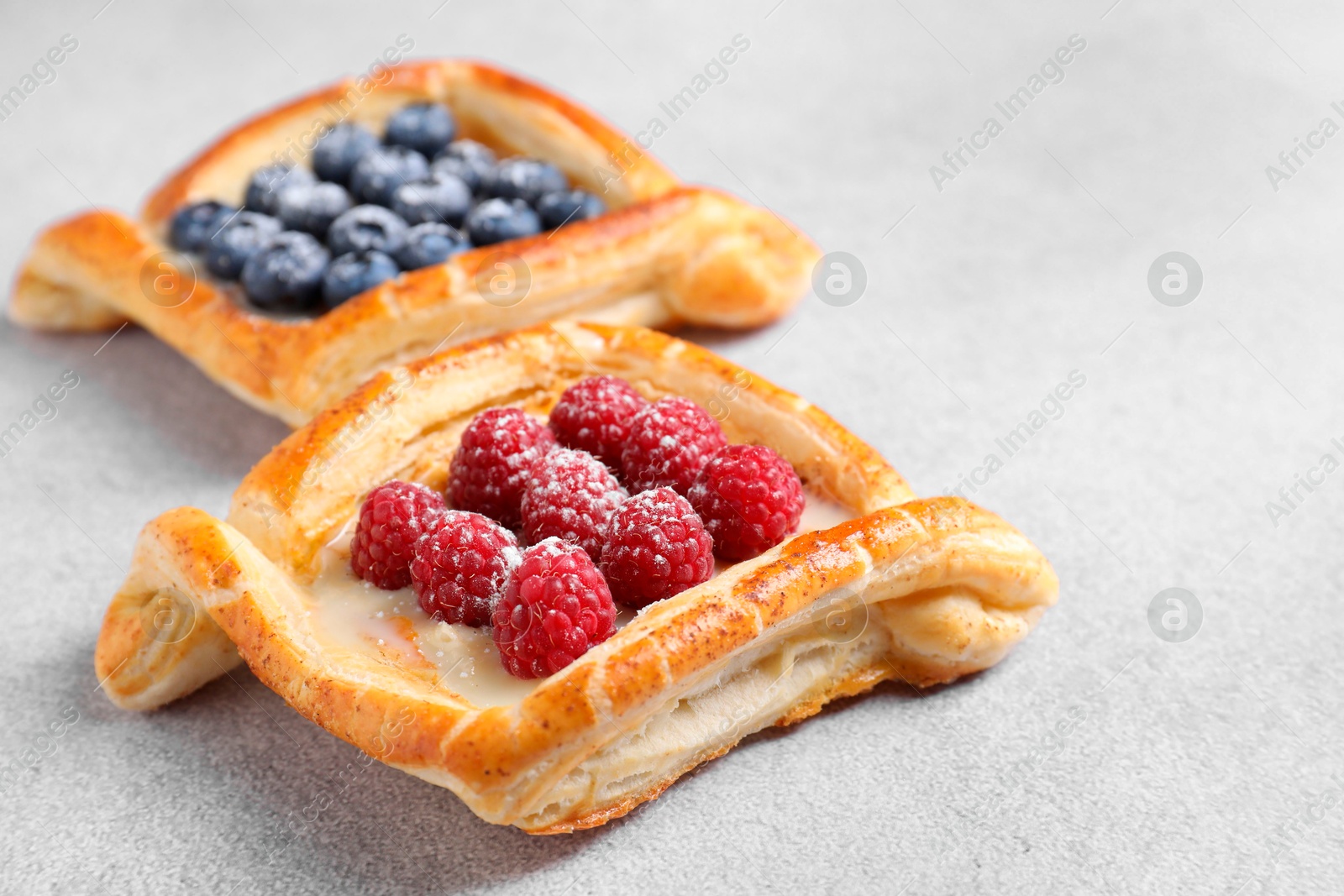 Photo of Tasty puff pastries with berries on white table, closeup. Space for text