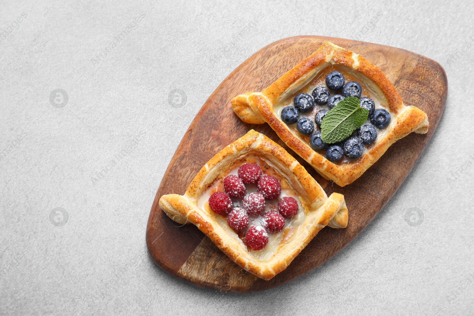 Photo of Tasty puff pastries with berries on white table, top view. Space for text