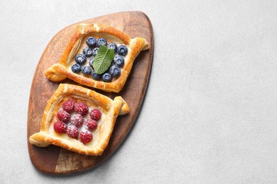 Photo of Tasty puff pastries with berries on white table, top view. Space for text