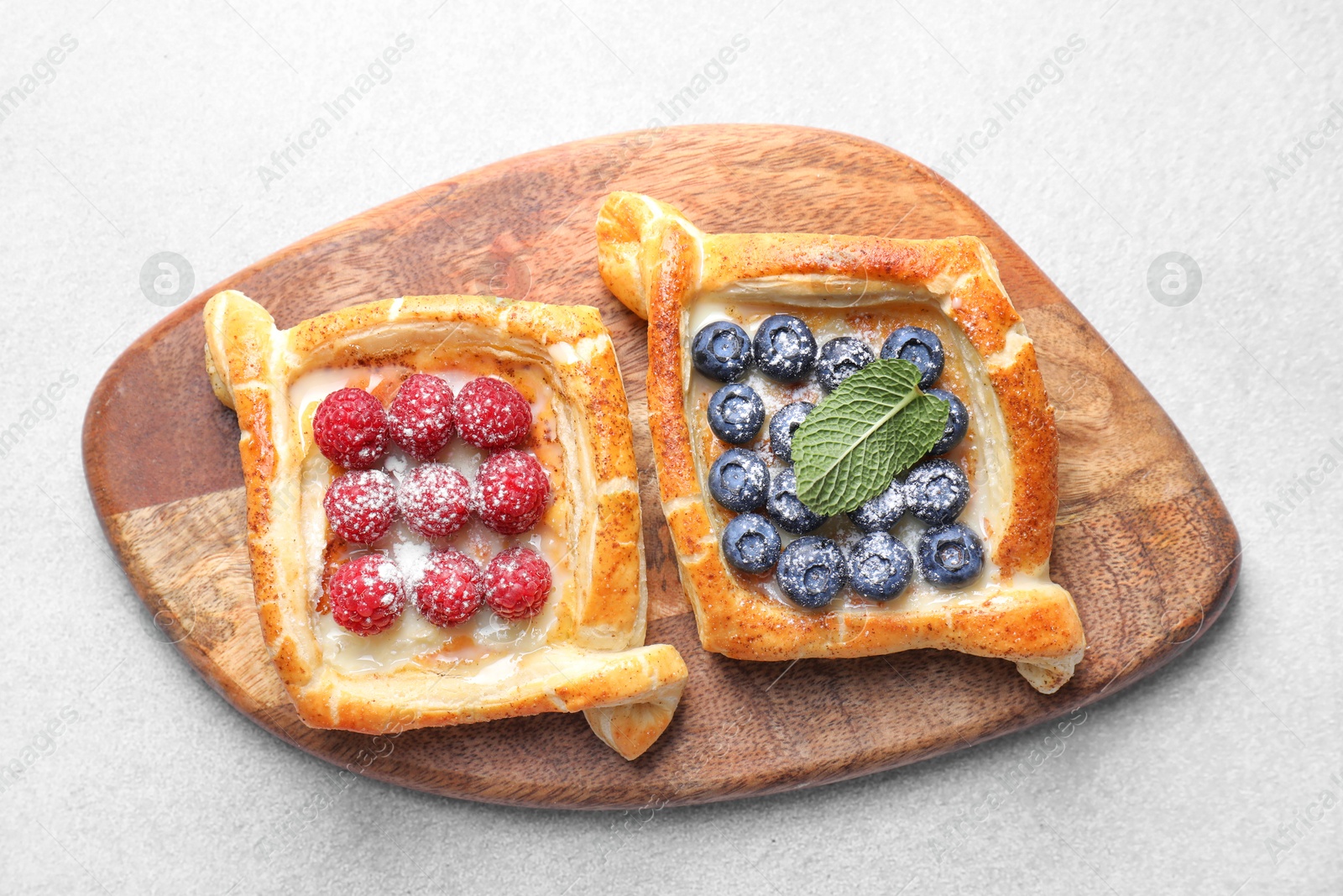 Photo of Tasty puff pastries with berries on white table, top view