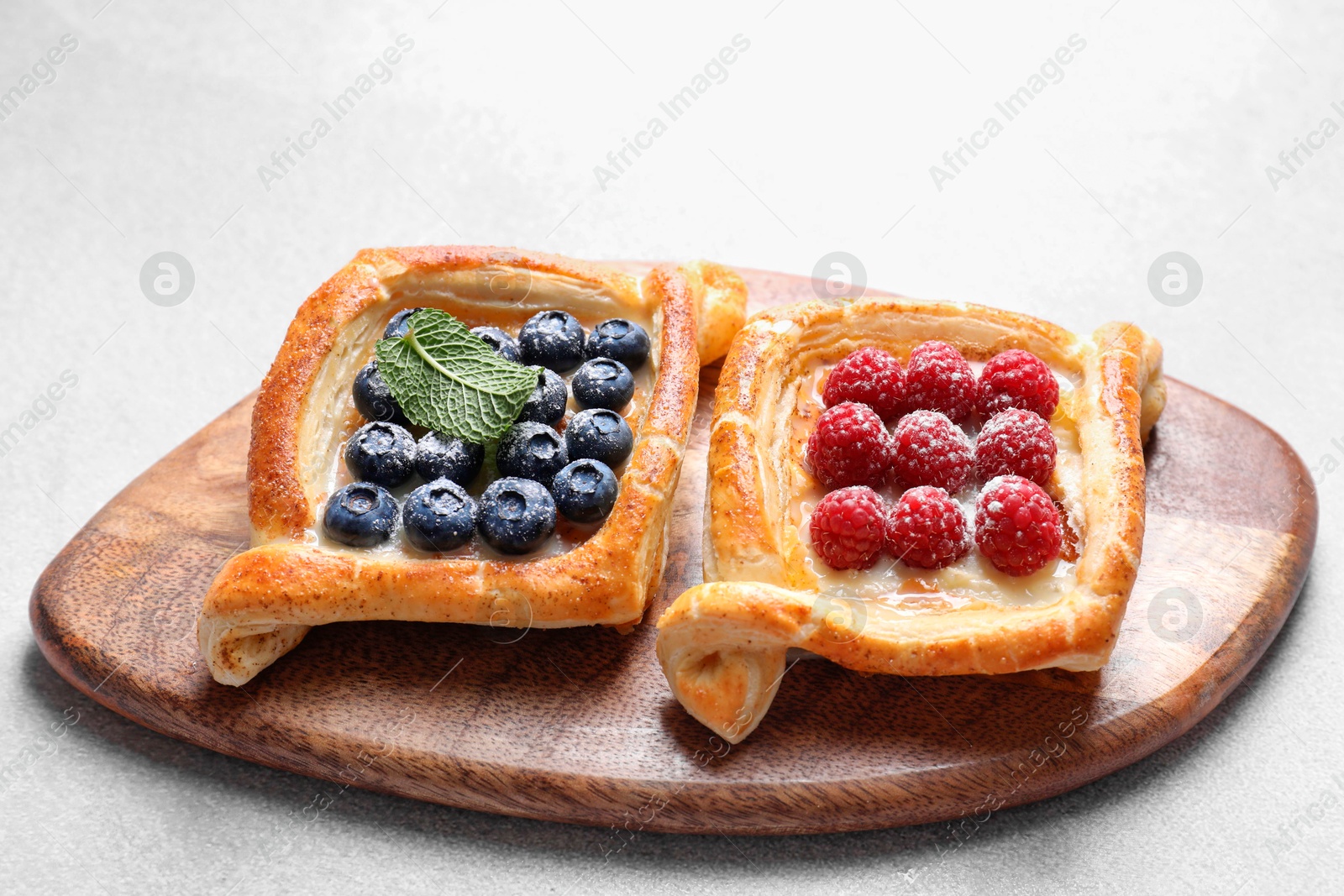 Photo of Tasty puff pastries with berries on white table