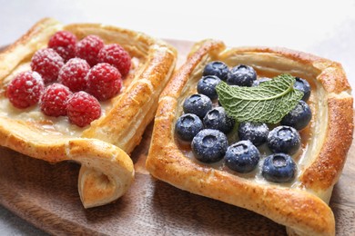 Photo of Tasty puff pastries with berries on white table, closeup