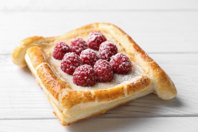 Photo of Tasty puff pastry with raspberries on white wooden table, closeup