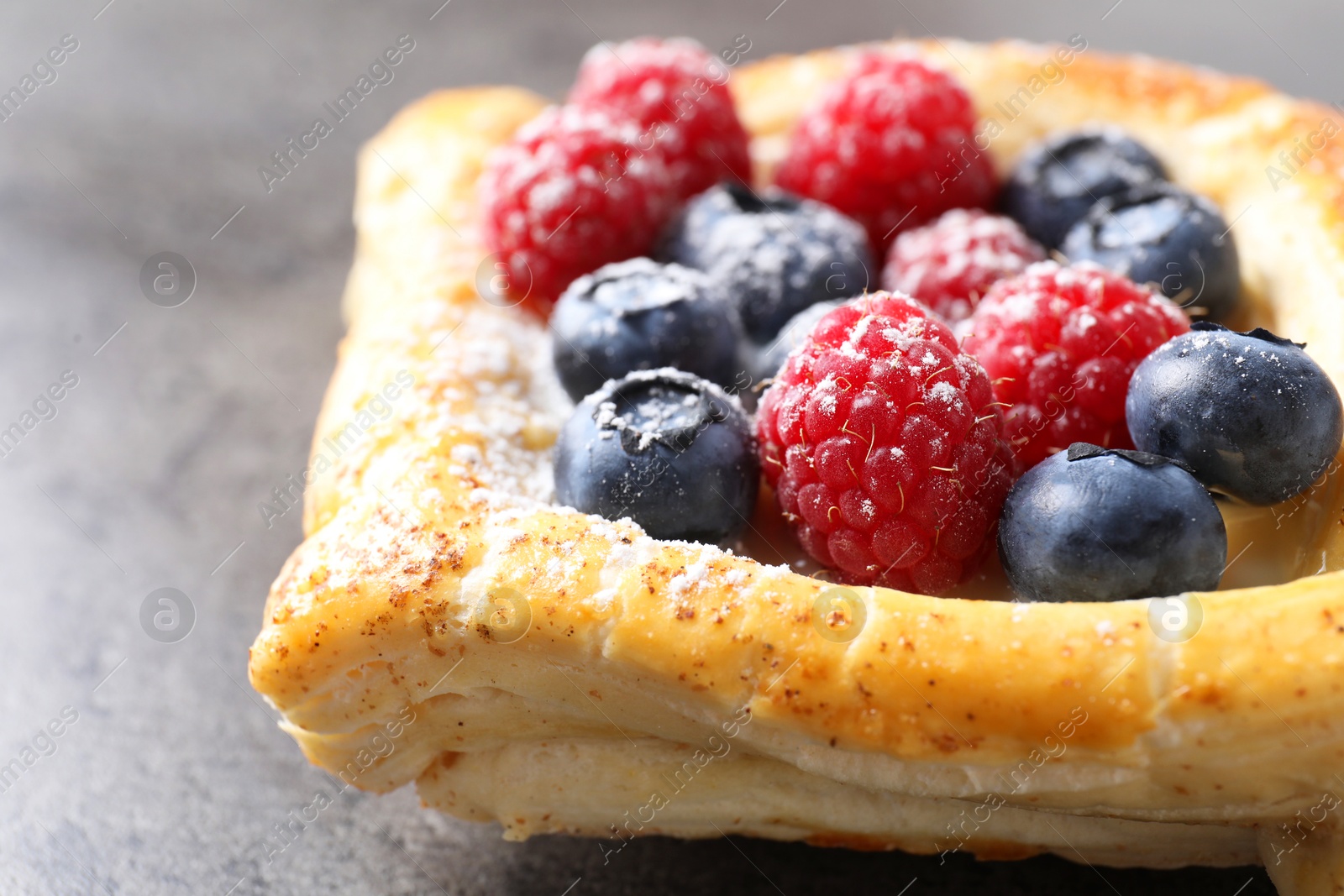 Photo of Tasty puff pastry with berries on grey table, closeup