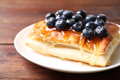 Photo of Tasty puff pastry with blueberries on wooden table, closeup