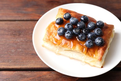 Photo of Tasty puff pastry with blueberries on wooden table, closeup