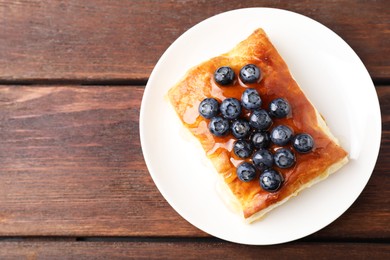 Tasty puff pastry with blueberries on wooden table, top view. Space for text