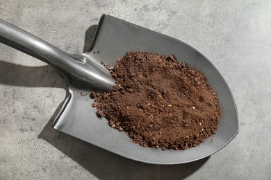 Photo of Metal shovel with soil on grey table, top view