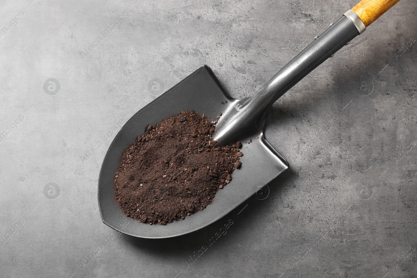 Photo of Metal shovel with soil on grey table, top view