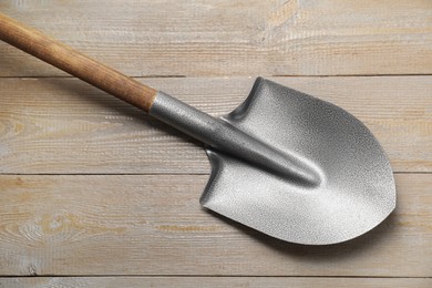 Photo of Metal shovel on light wooden table, top view